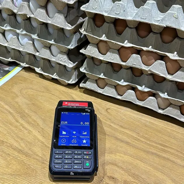 Kartenterminal vor gestapelten Eierpaletten