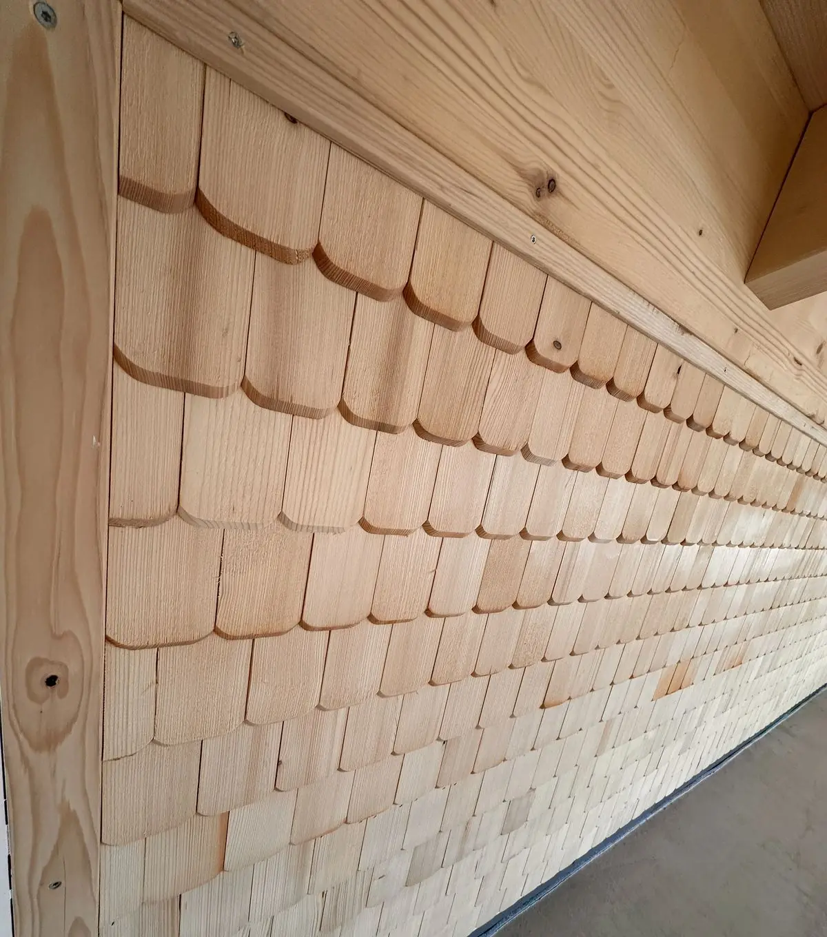 Helle Holzschindeln an der Wand des neuen Hofladens